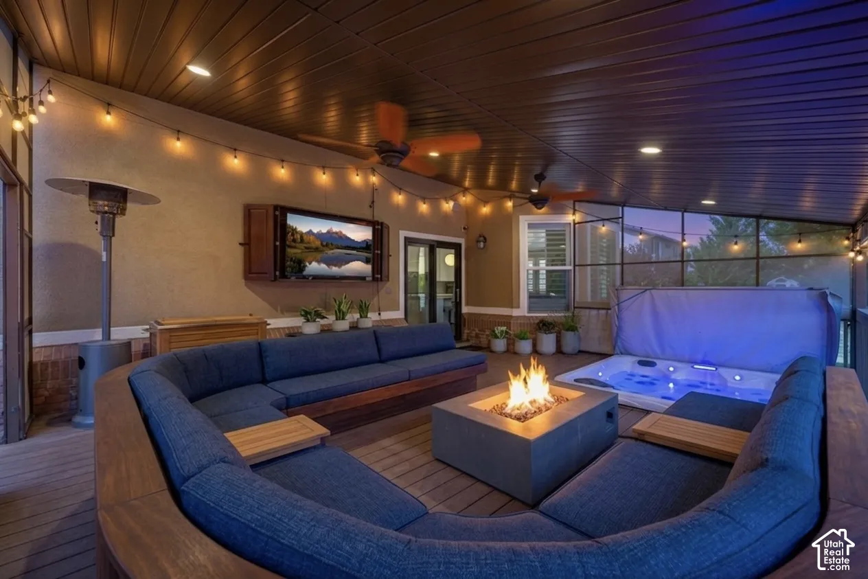 Covered outdoor patio featuring a built-in hot tub, concrete fire pit, and wood-finish decking