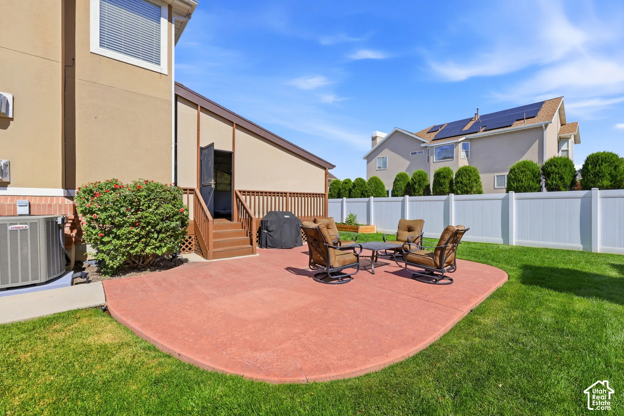 Expansive backyard featuring a stained concrete patio, lush green lawn, and a privacy fence