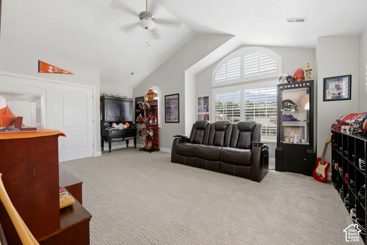 Vaulted ceiling room featuring light-toned carpeting and a ceiling fan