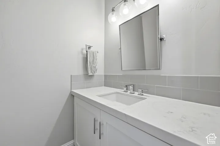 Bathroom vanity featuring a white countertop with integrated sink, chrome faucet, and rectangular mirror