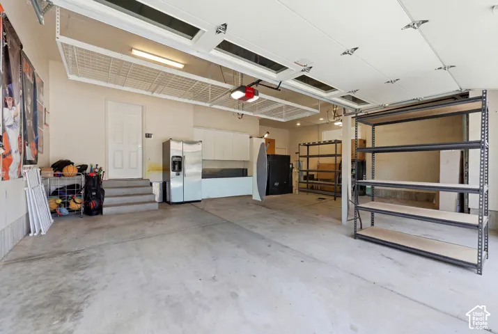 Spacious garage featuring concrete flooring, overhead storage racks, fluorescent lighting, and built-in shelving units