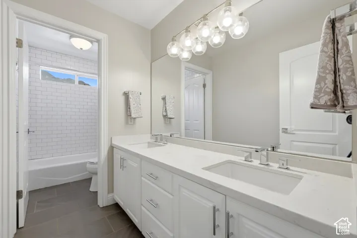 Bathroom featuring a double vanity with white cabinetry, integrated sinks, and chrome fixtures