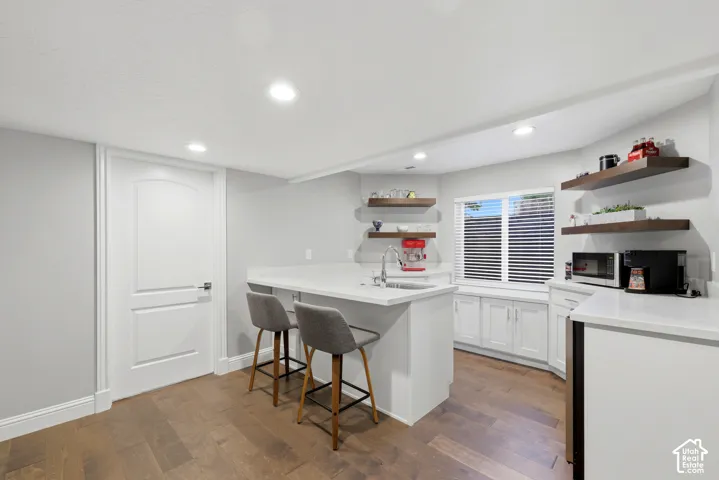 Contemporary kitchenette featuring white cabinetry, light-toned countertops, and wood-finish flooring