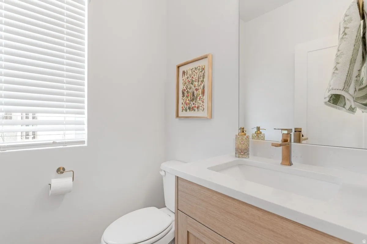 Bathroom featuring a modern vanity with light wood-finish cabinetry, an integrated white sink, and a bronze-finish faucet