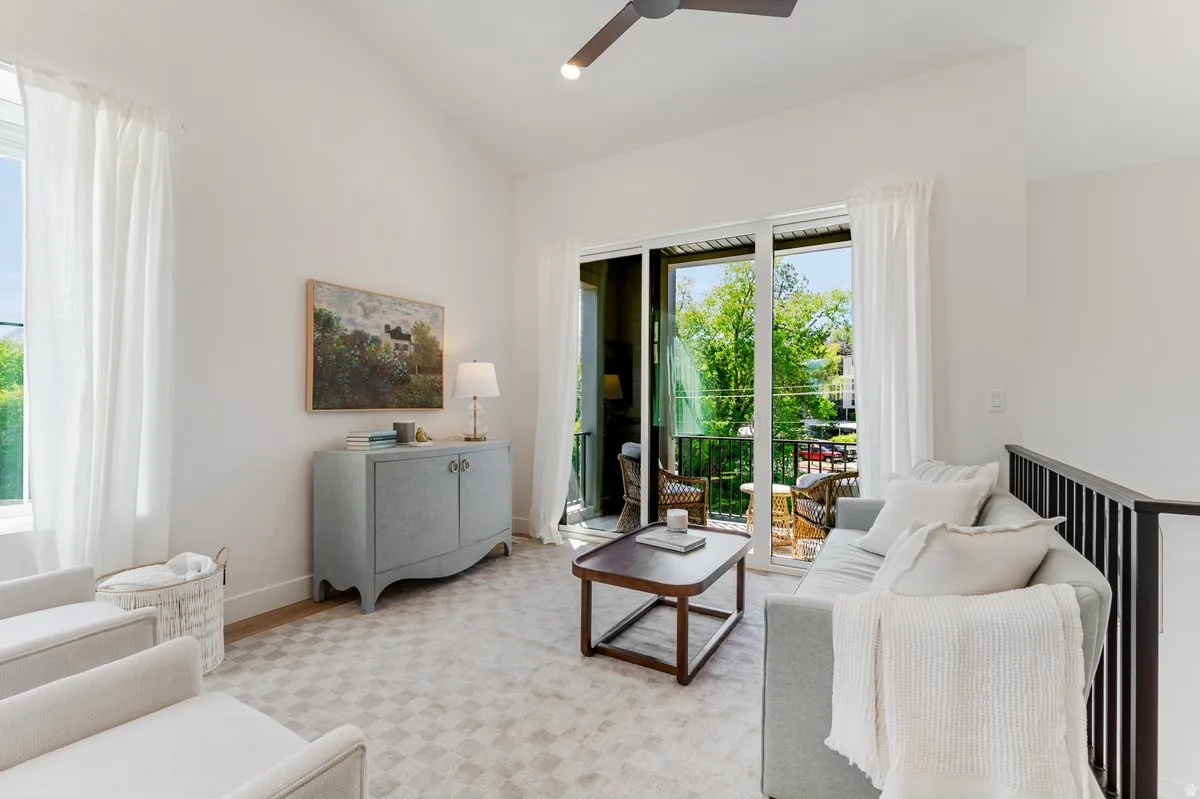 Bright room featuring vaulted ceilings, a sliding glass door opening to an outdoor balcony, an interior railing, and recessed lighting