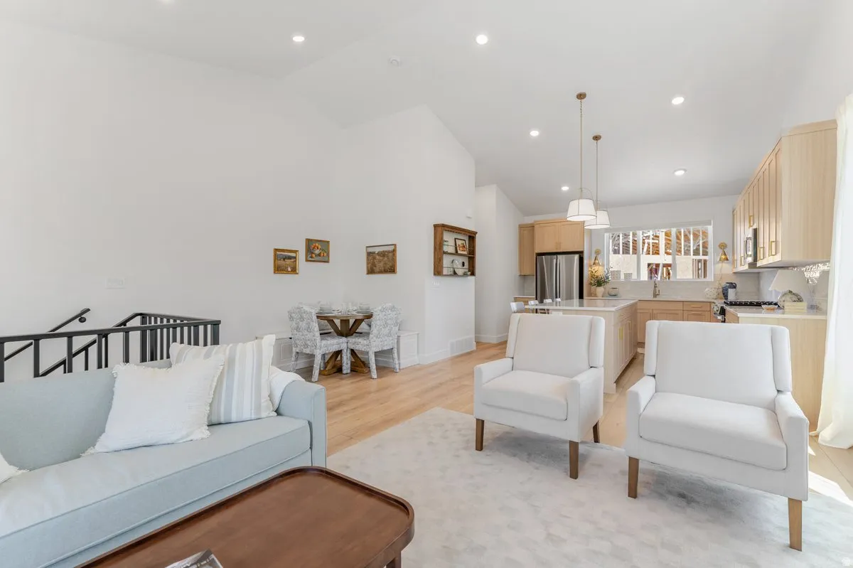 Open-concept living space featuring wood-finish flooring, recessed lighting, and a kitchen with light wood cabinetry