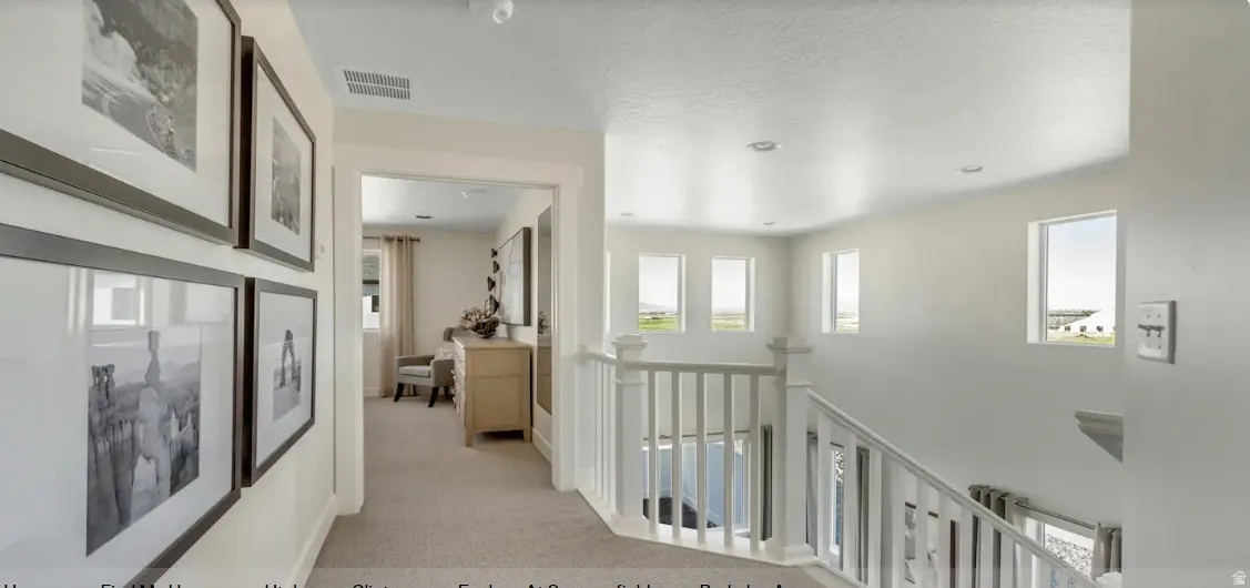Carpeted hallway leading to a bright landing with multiple windows and white wood balusters. PICTURE IS OF A SIMILAR HOME