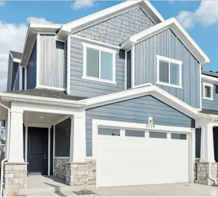 Modern facade featuring gray siding, white trim, stone accents, and a two-car garage with transom windows. PICTURE IS OF A SIMILAR HOME.
