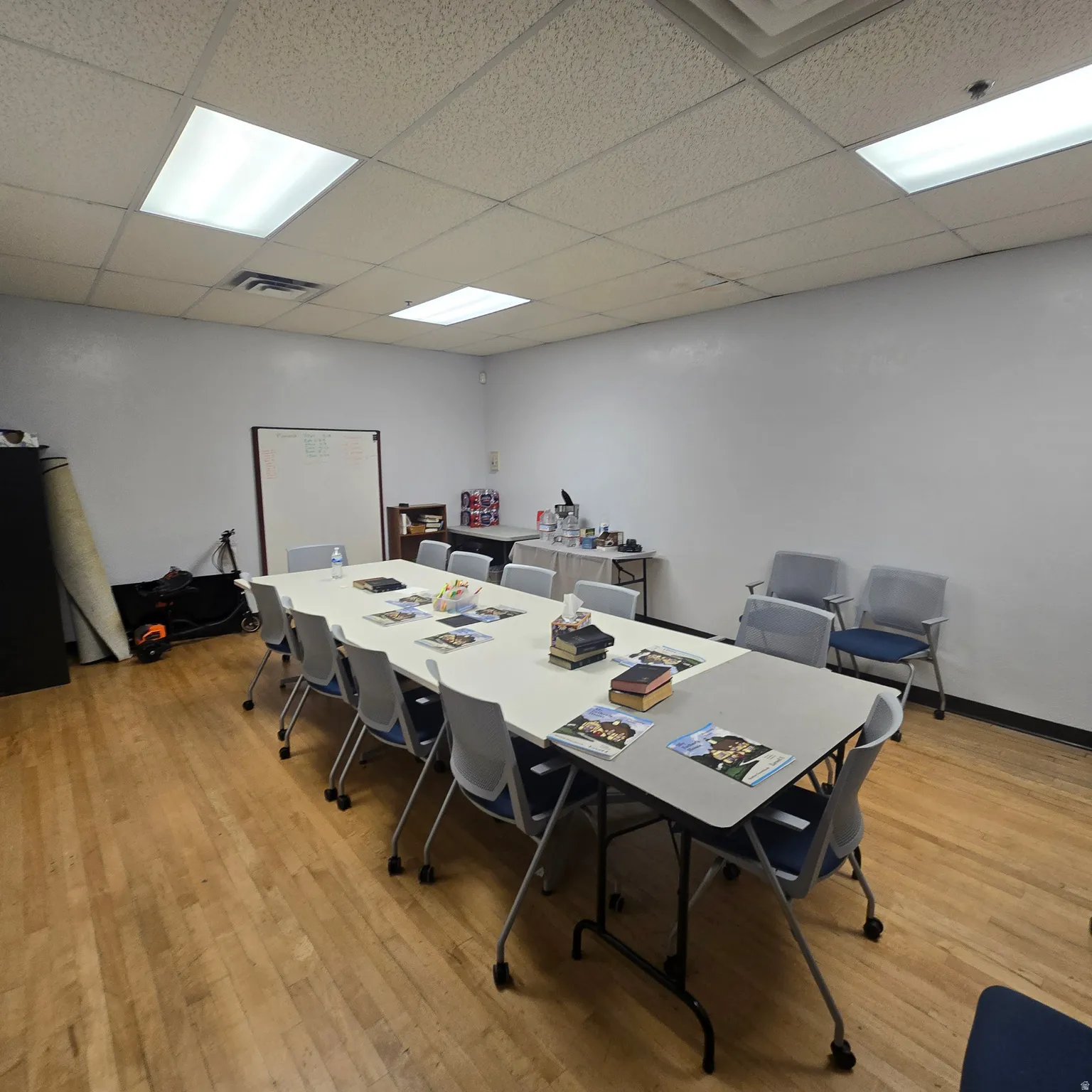 Spacious room featuring wood-finish flooring, white walls, and a dropped ceiling with recessed lighting