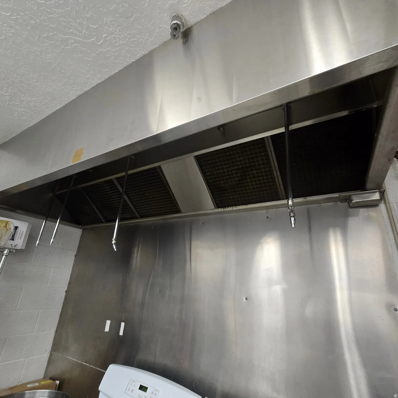 Stainless steel commercial-grade exhaust hood with integrated fire suppression system and baffle filters