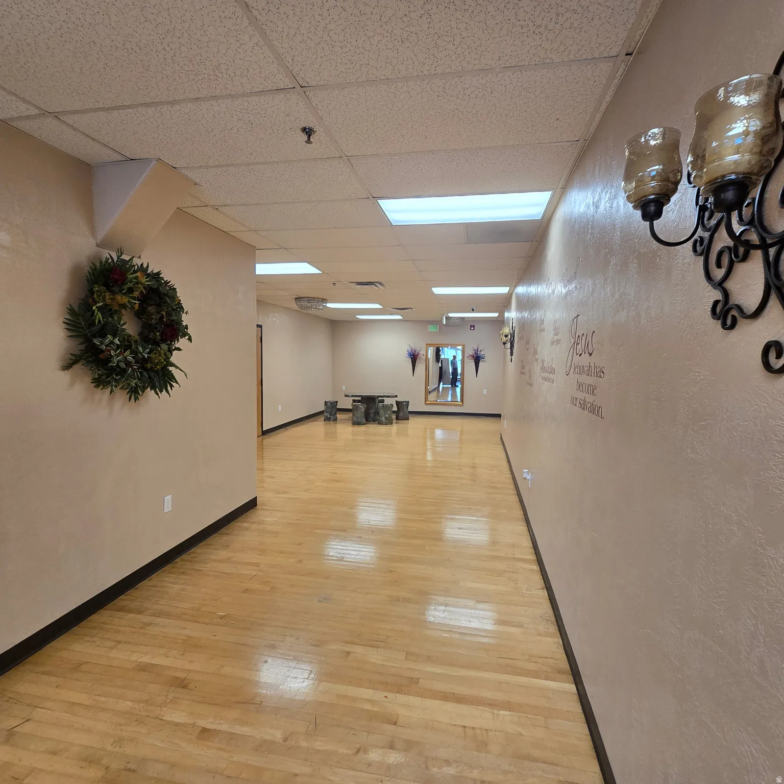 Spacious corridor featuring blonde wood-finish flooring, recessed lighting, and a drop ceiling