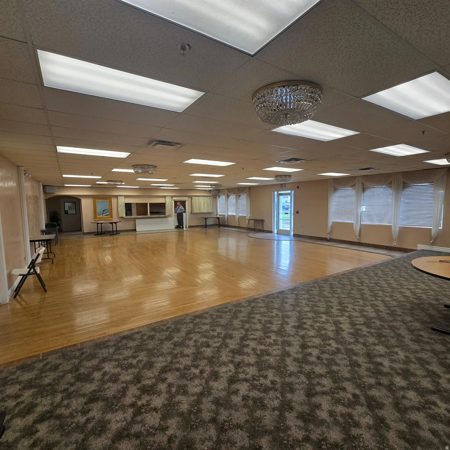 Spacious room featuring a combination of wood-finish flooring and patterned carpeting