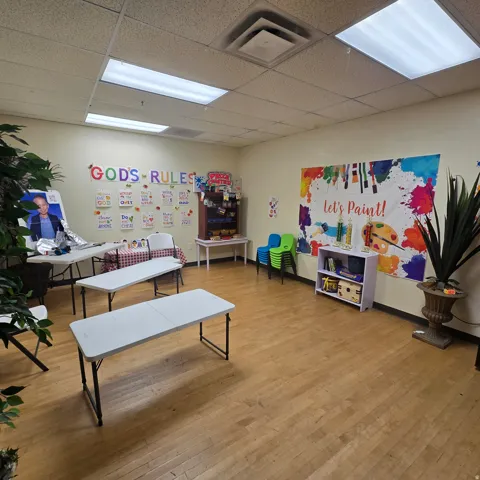 Spacious room featuring wood-finish flooring, drop ceiling with integrated fluorescent lighting, and light-toned walls