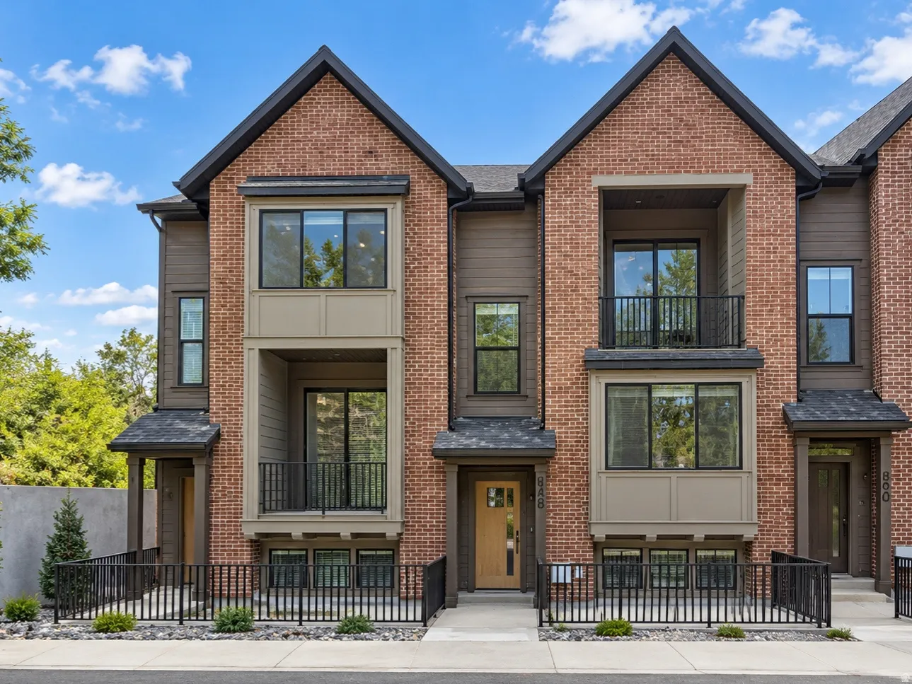 Brick and siding exterior with multiple balconies, a covered entry, and a contemporary architectural style