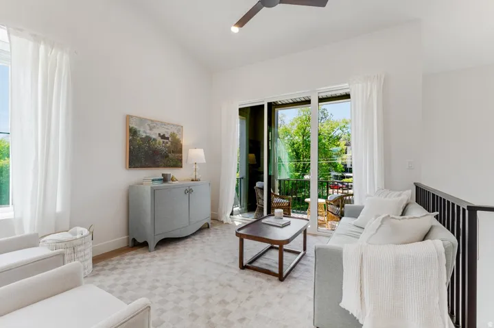 Bright room featuring vaulted ceilings, a sliding glass door opening to an outdoor balcony, an interior railing, and recessed lighting