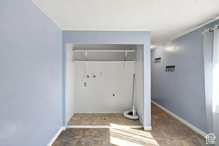 Utility space featuring built-in shelving, water hookups, and a window with sheer curtains
