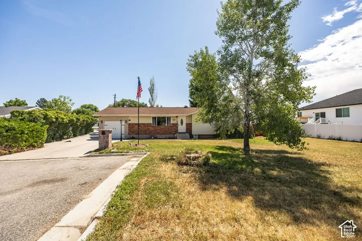 Ranch-style residence featuring a brick facade accent, an attached garage, and a paved driveway