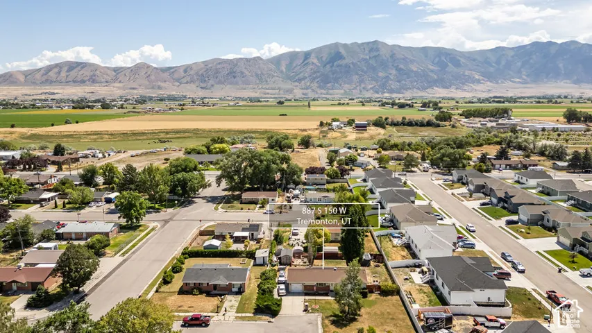 Aerial perspective showcasing a residential neighborhood with surrounding fields and distant mountains