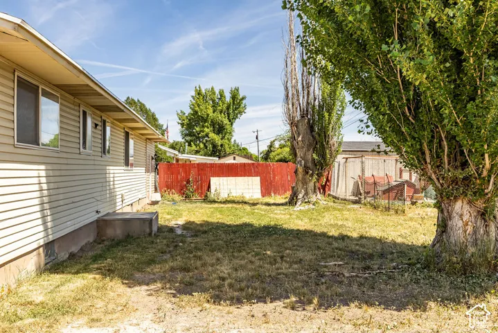 Expansive backyard with established trees and a vibrant red privacy fence