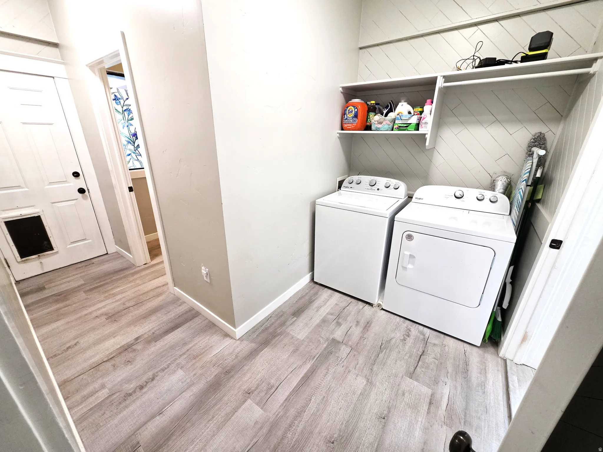 Dedicated laundry area featuring a washer and dryer, wood-finish flooring, and built-in shelving