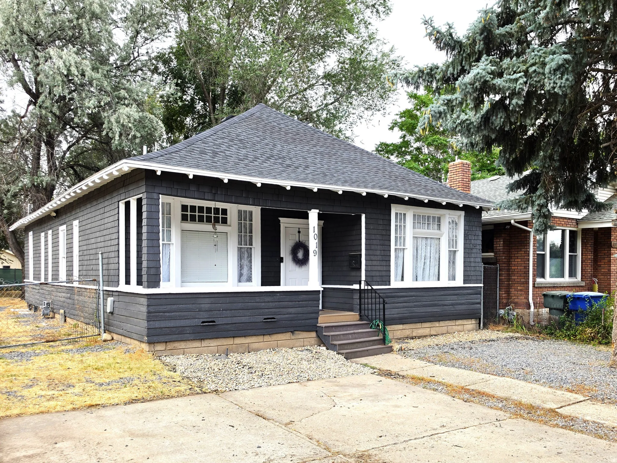 Bungalow-style home featuring dark gray shake siding and white trim