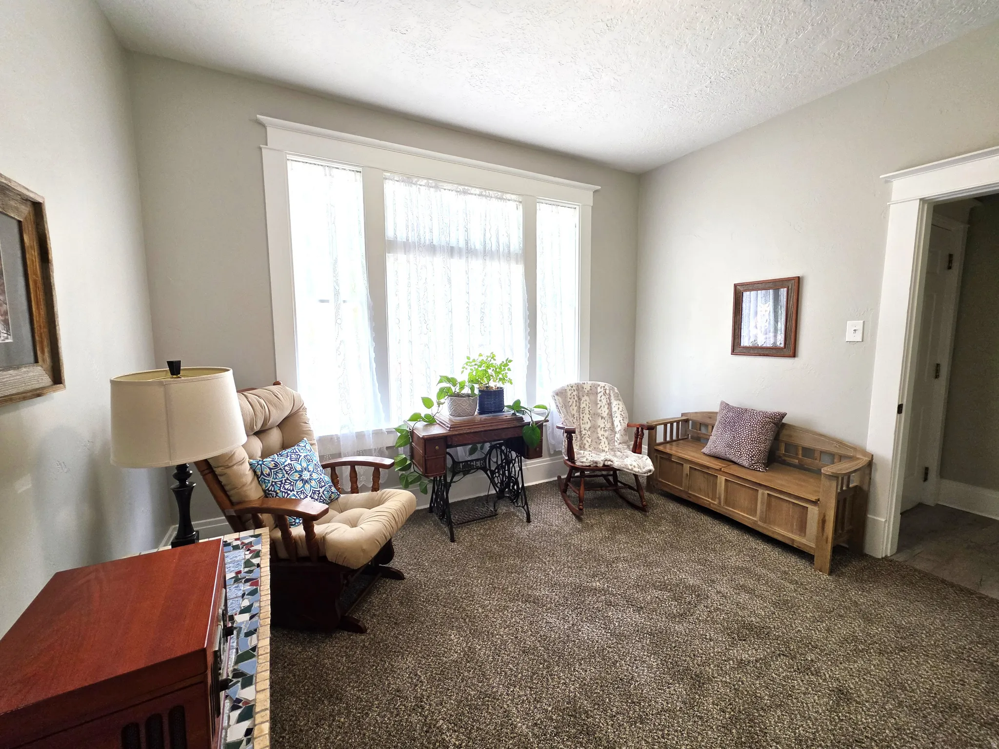 Room featuring a large window with white trim, light-colored walls, and brown carpet flooring