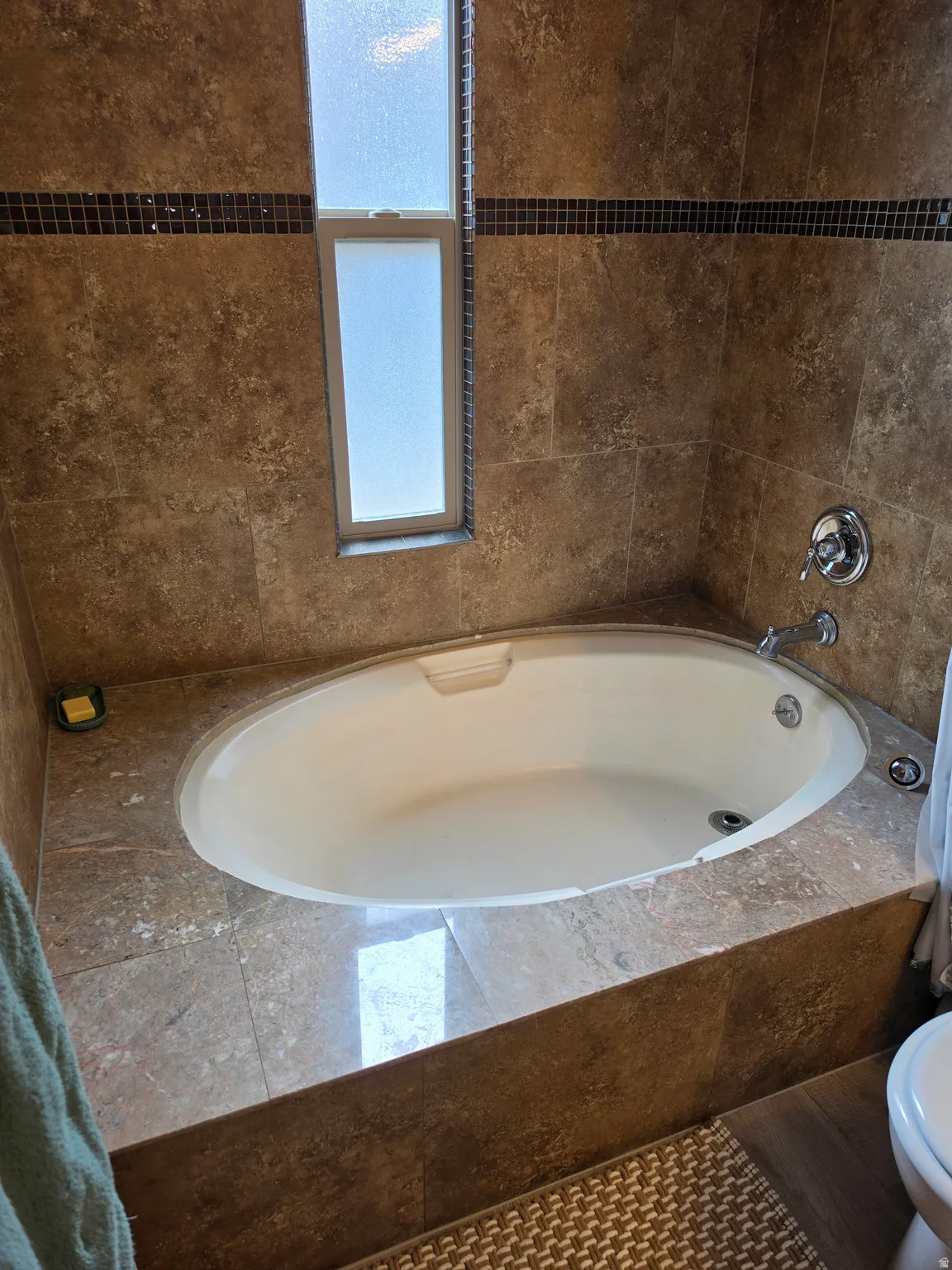 Built-in bathtub featuring a tiled surround and an integrated window