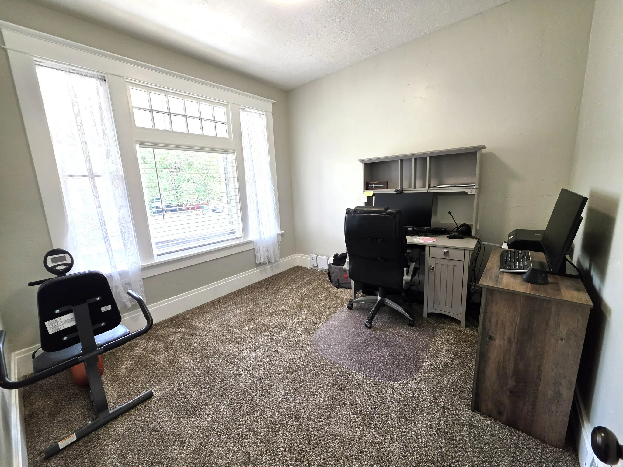 Room featuring a large window with transom, white trim, and light gray walls