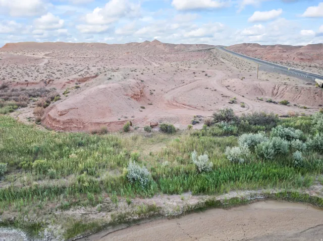 Expansive landscape featuring diverse terrain with a highway in the distance, a natural water feature, and varied vegetation
