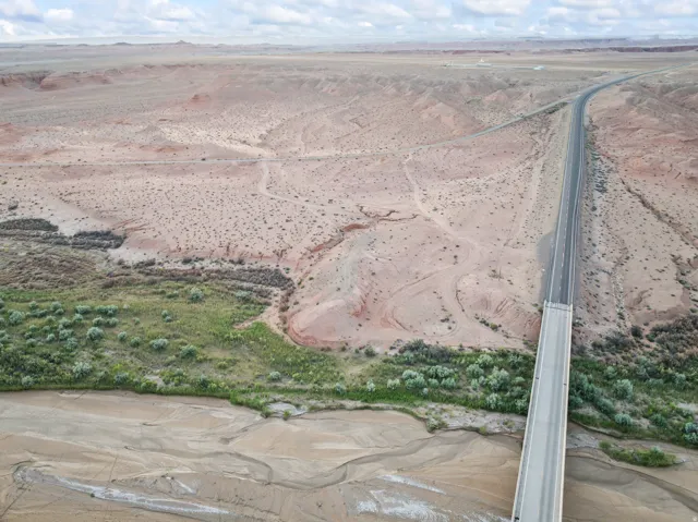 Aerial perspective of expansive desert terrain featuring a substantial bridge structure