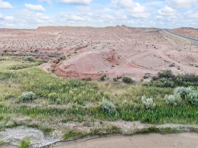 Expansive desert terrain featuring a distant paved road, natural dry creek bed, and varied desert flora
