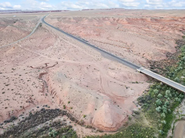 Expansive desert landscape featuring a paved highway, a bridge structure, and natural rock formations