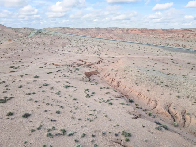 Expansive desert landscape featuring natural terrain and a distant roadway