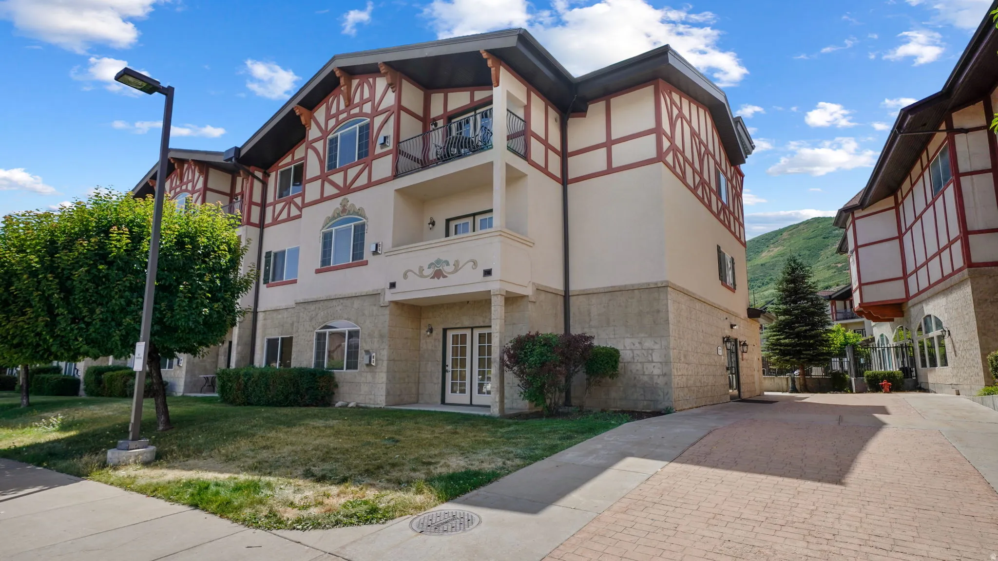 Multi-story structure featuring a stucco and stone veneer exterior with decorative half-timbering, showing french doors to private small patio on main level