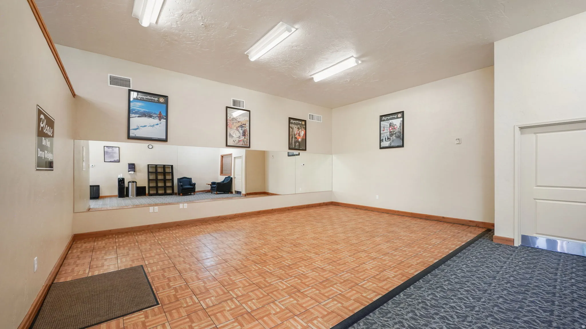 Dedicated activity room featuring a wood-finish dance floor, full-length wall mirrors, and recessed overhead fluorescent lighting