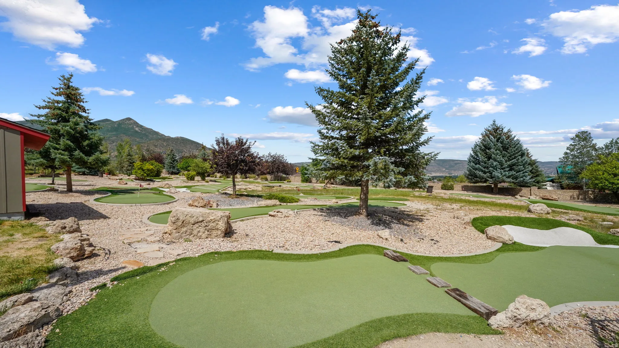 Expansive outdoor space featuring a multi-hole putting green with sand traps and stone accents