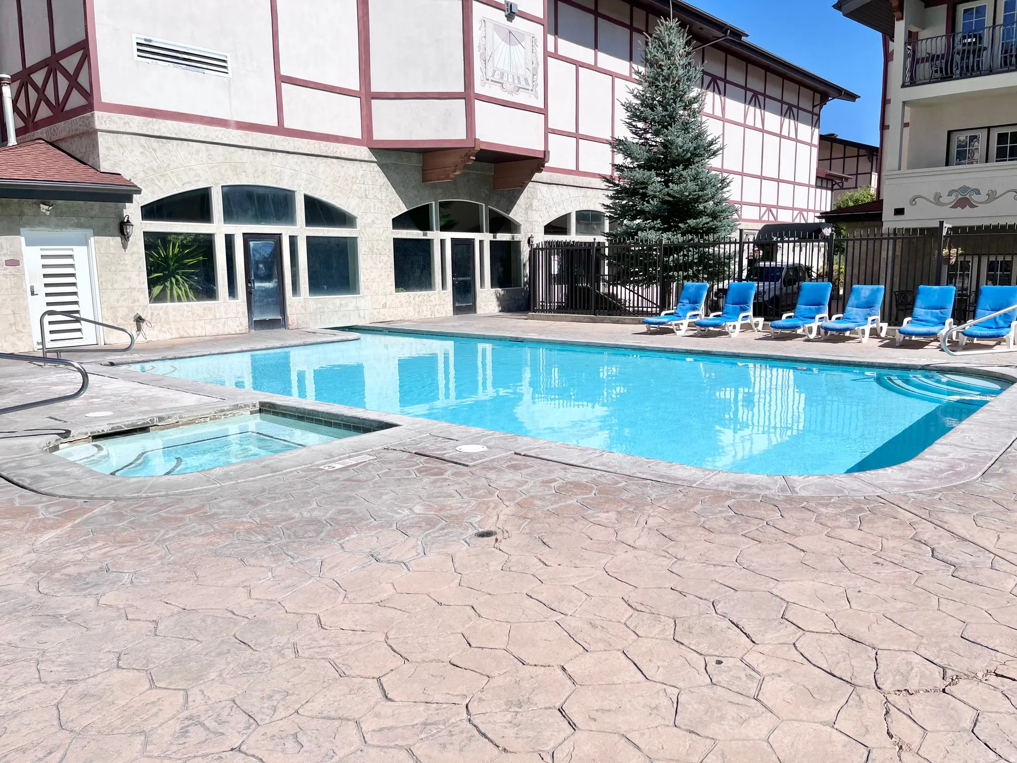 Outdoor pool featuring a built-in spa, stamped concrete decking, and perimeter fencing