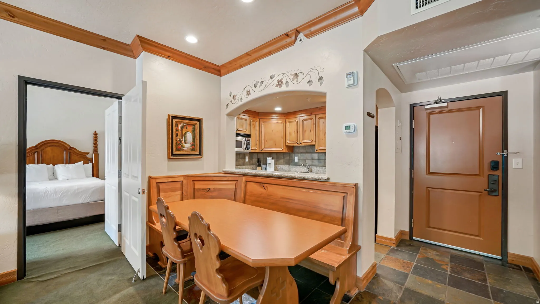 Dining area featuring a built-in wooden booth with a coordinating table, recessed lighting, and a pass-through opening to the kitchen and lock out access to second bedroom