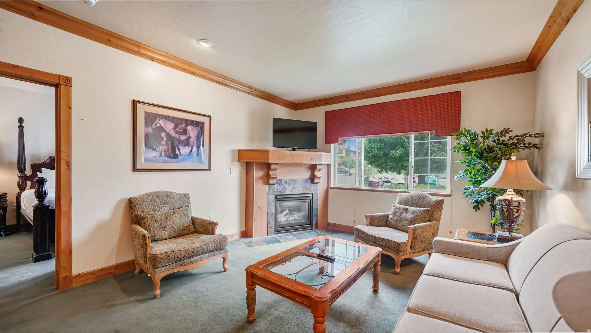 Living area featuring a stone-faced fireplace with wood mantel, a window offering exterior views, and wood trim accents