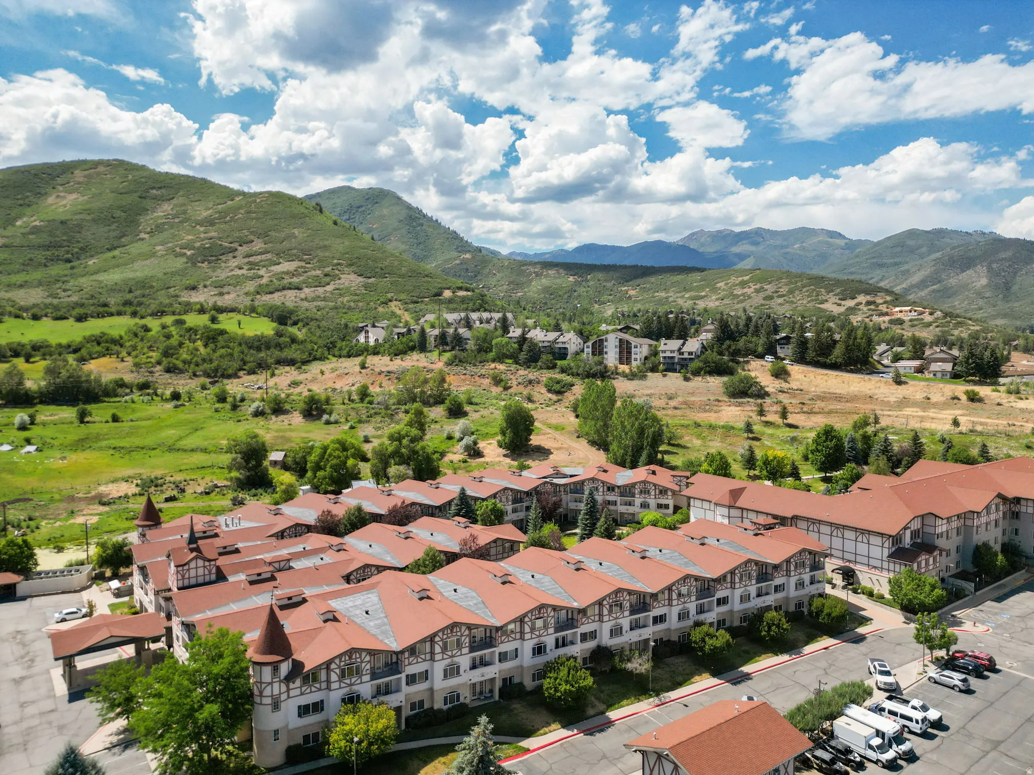 Extensive multi-building property featuring traditional European architectural elements, peaked terracotta-toned roofs, and a backdrop of verdant mountains