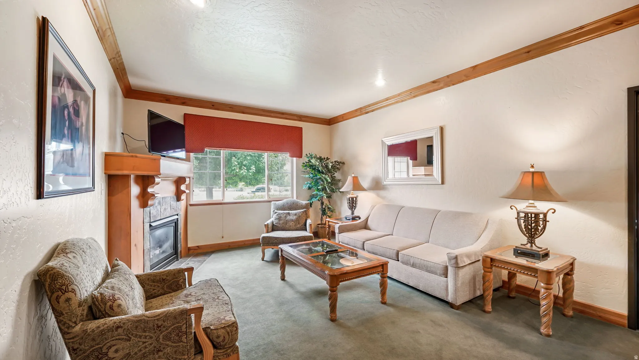 Living area featuring a fireplace with a stone surround and wood mantel, large window with a red valance, wood-finish ceiling trim, and recessed lighting