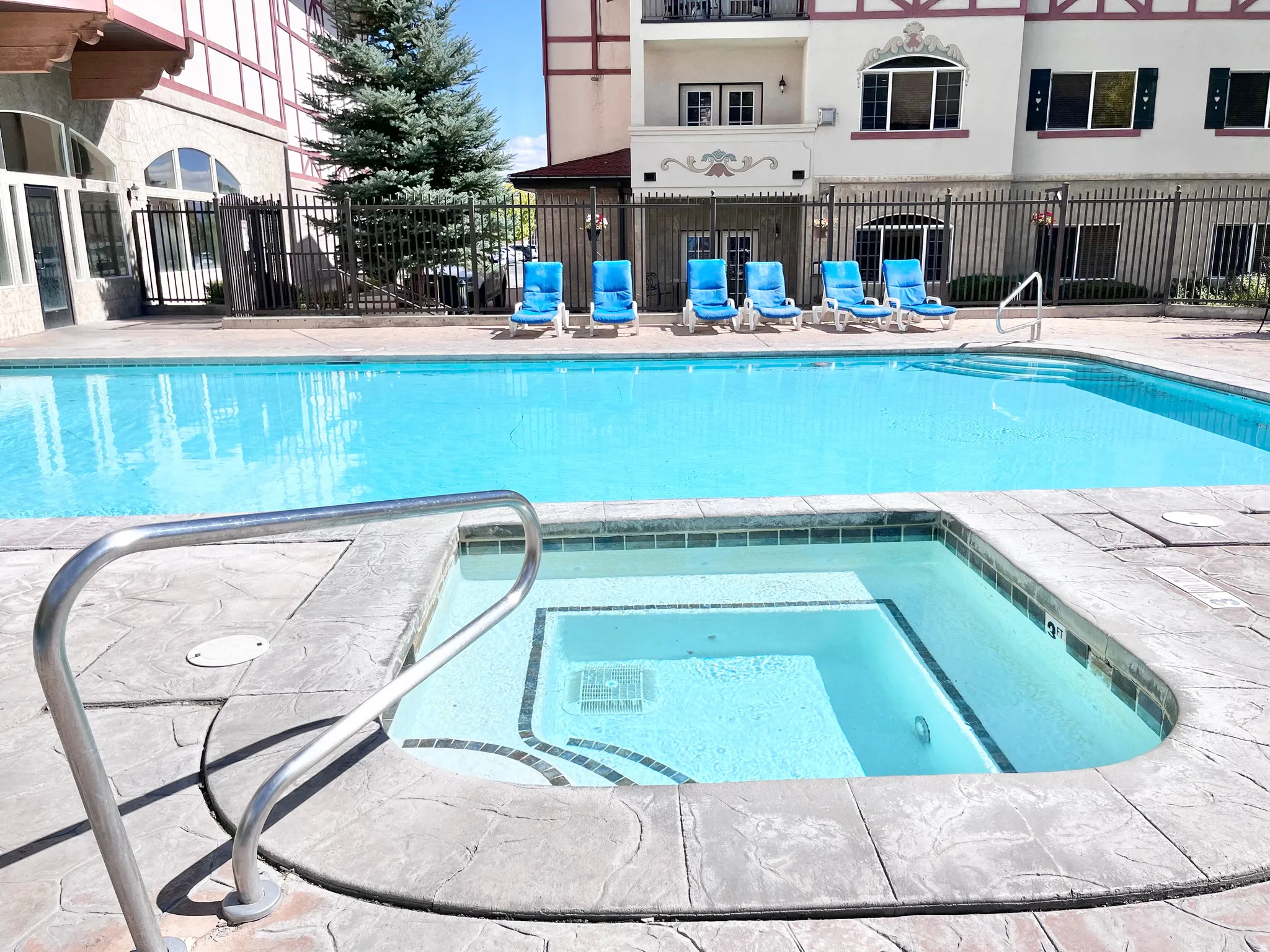 Resort-style pool area featuring a rectangular pool and an integrated hot tub
