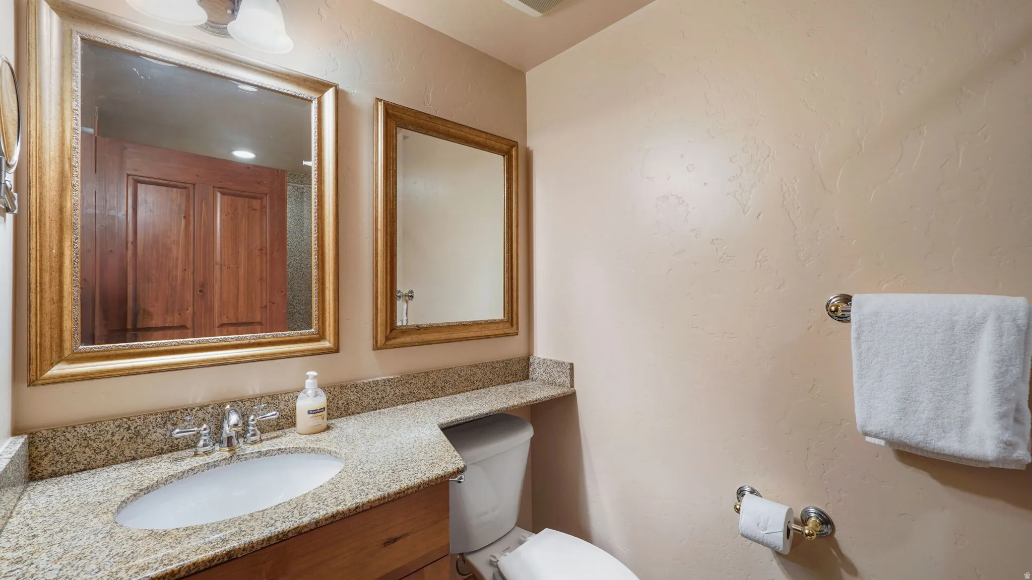 Second bathroom featuring a polished countertop, undermount sink, and dual framed mirrors
