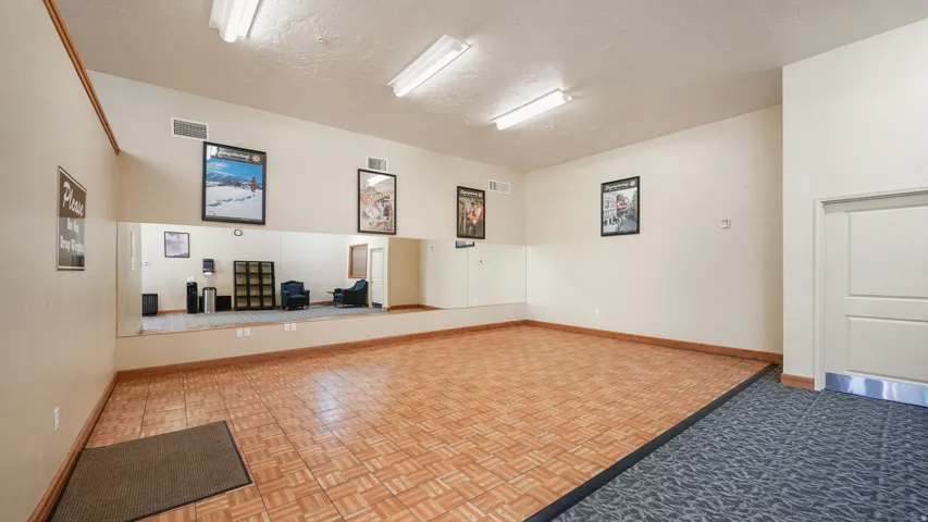 Dedicated activity room featuring a wood-finish dance floor, full-length wall mirrors, and recessed overhead fluorescent lighting