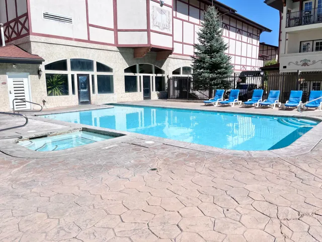 Outdoor pool featuring a built-in spa, stamped concrete decking, and perimeter fencing