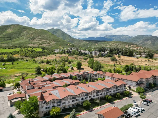 Extensive multi-building property featuring traditional European architectural elements, peaked terracotta-toned roofs, and a backdrop of verdant mountains