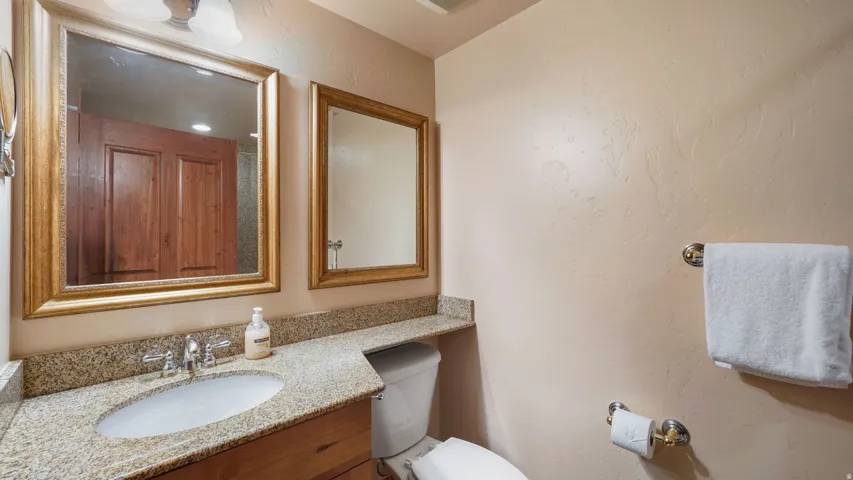 Second bathroom featuring a polished countertop, undermount sink, and dual framed mirrors