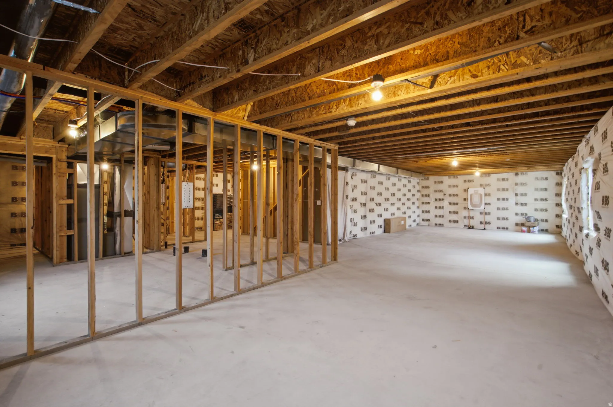 Unfinished basement featuring extensive framing, exposed ceiling joists, concrete flooring, and insulated walls
