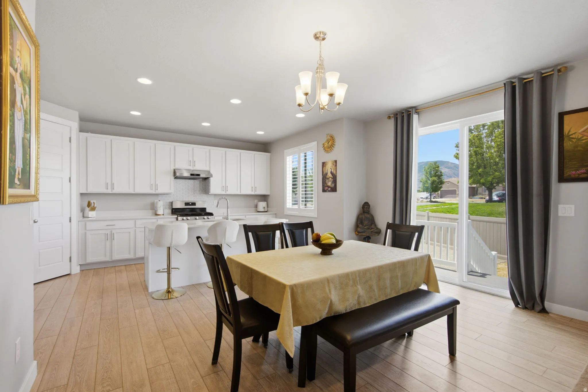 Open-concept living space featuring wood-finish flooring, white cabinetry, recessed lighting, and a chandelier