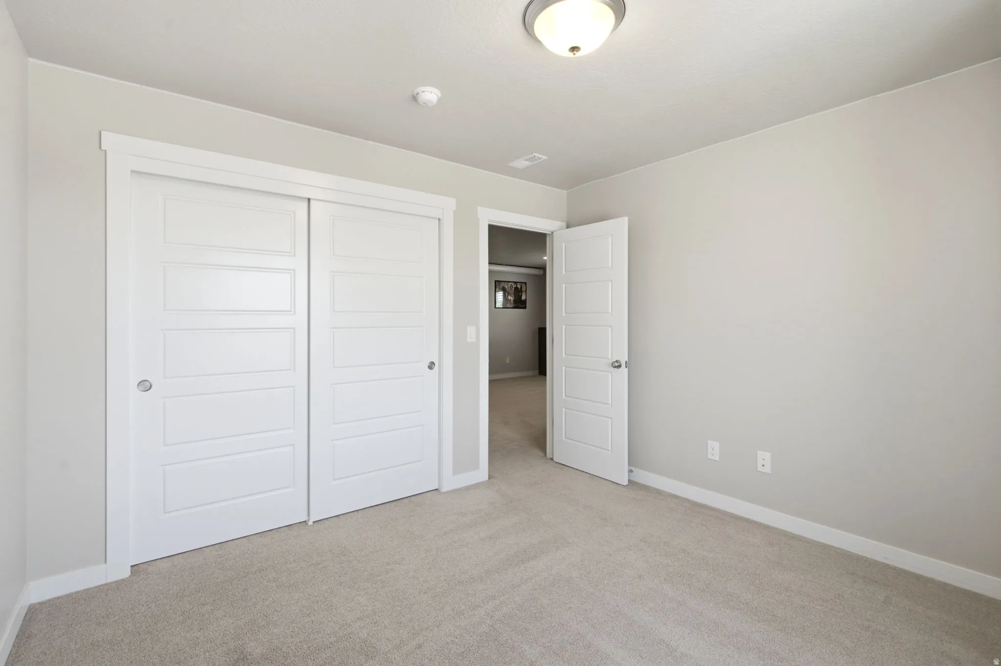 Neutral-toned room featuring a ceiling-mounted light fixture, light gray walls, and carpet flooring